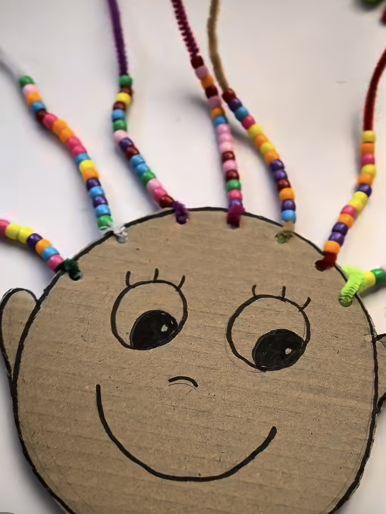Cardboard face craft with colorful beads threaded into the hair